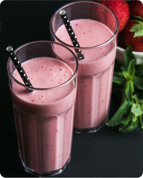 two glasses of pink smoothies with identical black polka dot straws